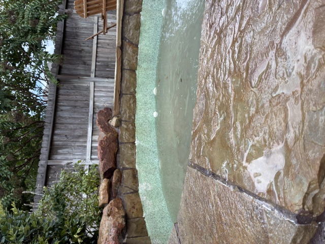 After: Wet, irregular flagstone paving meets the curved stone edge of a backyard pool.